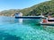 A pier at the foot of Mount Athos in Greece. Clear sea water, a dry cargo ship, a small boat and a forest in the