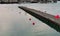 Pier on the harbor with red buoys and reflections in the water at sunset