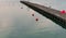 Pier on the harbor with red buoys and reflections in the water at sunset