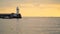 Pier with a lighthouse in the evening. The boat sails past