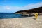 Pier oceanscape with a sandy beach and yellow lifebuoy rings  and rocky, forested hills