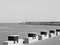 The pier of Pesaro harbor with a lighthouse, tetrapods and a series of wooden tables with stone benches placed on the edge