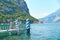 Pier or quay for ships and boats on steep alpine banks of beautiful lake Como with parked boats and yachts near village