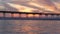 Pier in sea water on beach. Ocean waves, sky at sunset. California coast vibes.