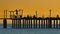 Pier silhouette with people on it over sunrise glow. Mediterranean gold dawn