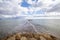 A pier of stones, a pier going into the sea. Dramatic sky with dark, heavy clouds. Copy space