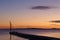 Pier before sunrise with birds sitting on a small crane silhouetted against the morning sky