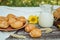 Pies or buns and a mug of homemade farm fresh milk, sunflower, baked goods and bread with flax seeds on a wooden background