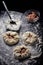 Pies with meat, potatoes and onions. Bowls with flour and tartar. The process of preparation on a black background.