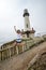 Pigeon Point Lighthouse - California - an adult female jumps in front of the light house on a cloudy foggy day