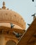 Pigeons, Doves, flying across old monumental building and museum, Mohatta Palace, tomb in background