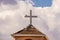 Pigeons roosting on a roof and on a cross against a dramatic cloudy sky