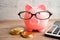 Pigging bank wearing eyeglass with coins and calculator; saving bank education concept
