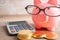 Pigging bank wearing eyeglass with coins and calculator; saving bank education concept