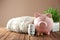 Piggy bank with coins, warm sweater and thermostat on wooden table. Heating saving concept