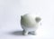 Piggy bank with coins. White ceramic moneybox