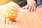 Piggy bank, coins and woman using calculator on wood table