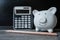 Piggy bank with distinctive pencil and a calculator showing savings and discipline