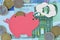 Piggy bank dreaming about house on euro banknotes and coins - Saving money for a house concept