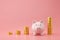 Piggy bank and golden stack coins of growing graph on pink background with saving money concept. Financial planning for the future