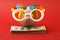 Piggy bank with Happy birthday party glasses standing on stack of money american hundred dollar bills on red background