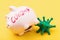 Piggy bank with the inscription and toy coronavirus on a yellow background