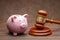 Piggy bank and judge gavel on wooden brown background