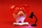 Piggy bank in love with red heart sunglasses reading a book and shining black lamp on red background