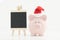 Piggy bank with a Santa Claus hat and a blackboard