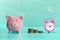 Between the piggy bank and a small pink alarm clock, three stacks of coins are in order. The symbol of the growth of