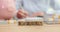 Piggy bank and stacks of money on office desk of person holding pen and writing