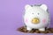 Piggy bank with steel chain and coins and lilac background. Money safety concept