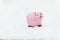 Piggy bank in traditional pink. Ceramic toy on white snow.