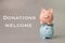 Piggy banks isolated on grey background with text DONATIONS WELCOME