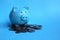 Piggy blue piggy standing on a pile of money coins