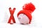 Piggy box with red hat with pompom standing next to red ski and ski sticks on snow and around are snowbound trees