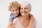 Piggyback, portrait and grandmother with child embrace, happy and bonding against a wall background. Love, face and