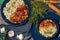 Pilaf bowl (plov, pilaw, pilau) on dark blue bowls decorated with ingridents on wood table top view.