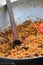 Pilaf in cauldron. A delicious pilaf with pork, carrots and rice with spicy spices and onions, in a cauldron with a wooden spatula
