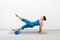 Pilates, core and glutes training. Fit caucasian woman practice reverse plank drill with foam roller, one leg up in loft