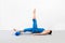 Pilates with foam roller indoor. Adult fit caucasian woman in blue sportswear lying on back and practice scissors