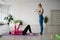 Pilates instructor trains a woman in sportswear in the gym, corrects posture. Rehabilitation after injury. Copy space.