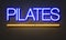 Pilates neon sign on brick wall background.