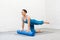 Pilates with props indoor. Fit smiling woman in blue sportswear practice bird dog drill with foam roller under her hands