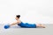 Pilates workout indoor. Caucasian attractive woman in blue sportswear lying on front and practice swan drill on a foam