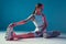 Pilates workout. Modern slim sports girl stretching legs muscles sitting on floor in pink neon light. Long exposure