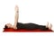 Pilates or yoga. A slender athletic girl lies on her back on a mat with her hands raised in the air.