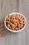 Pile of almonds nut in a while bowl against wooden background select focus shallow depth of field