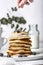 Pile of american pancakes with blueberries. Woman`s hand sifting with powdered sugar.