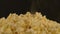 Pile of appetizing popcorn with dissipating steam. Woman's hand takes freshly cooked hot popcorn. Close up